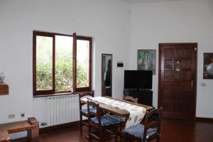 ein Wohnzimmer mit einem Tisch, Stühlen und Fenstern in der Unterkunft Froggy House in San Lorenzo al Mare