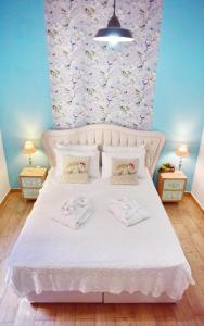 een slaapkamer met een wit bed met roze bloemen aan de muur bij Villa Mariza 1920 in Rhodos-stad