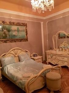 een slaapkamer met een bed, een dressoir en een kroonluchter bij Ádám Apartmanház in Szeged