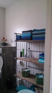 a bathroom with wooden shelves with blue towels at de Vloedlijn in Callantsoog