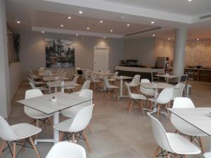 a dining room with tables and white chairs at Hotel Puerta del Mar - Adults Recommended in Nerja