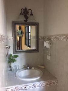 y baño con lavabo y espejo. en Hotel San Miguel Arcangel, en Izamal
