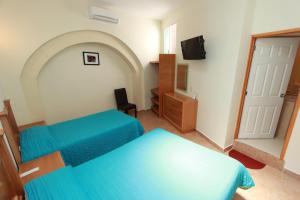 a bedroom with two blue beds and a tv at Hotel Santa Rita in Guanajuato