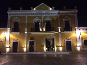 Un grand bâtiment jaune avec balcon est disponible la nuit. dans l'établissement Hotel San Miguel Arcangel, à Izamal