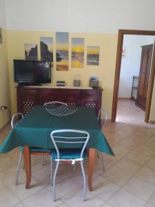 a dining room with a green table and chairs at Casa di Rosa in Chia