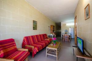 a living room with a red couch and a table at Kaccatur Flats in Marsalforn