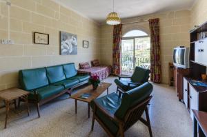 sala de estar con sofá, sillas y TV en Maryanne-Joe Flats, en Marsalforn