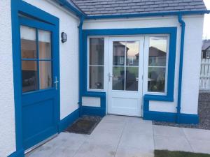niebieskie frontowe drzwi białego domu w obiekcie Olavat Cottage detached property with parking w mieście Inverness