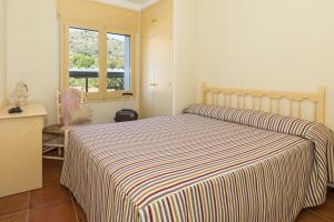 a bedroom with a bed with a striped blanket at Apartament Cap de Vol in Port de la Selva