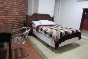 a bedroom with a bed and a brick wall at Hotel Nuevo Tio in Valledupar