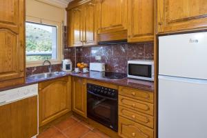 een keuken met houten kasten, een wastafel en een koelkast bij Apartament Cap de Vol in Port de la Selva
