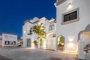 a white house with a palm tree in front of it at Valentina Suites by Las Flores Vacation Rentals in Playa del Carmen