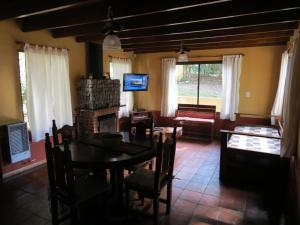 sala de estar con mesa, sillas y TV en Cabañas Calma Chicha en Sierra de los Padres