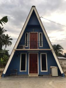 a blue house with a pointed roof with a red door at Panorama Homestay in Jeram