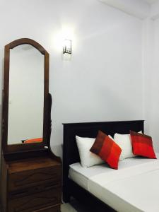 een slaapkamer met een spiegel en een bed met kussens bij Sunhill Lake Tourist Rest in Anuradhapura