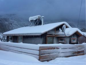 a building covered in snow with snow on the roof at Refugio Simple Sur Casa 4 personas in Malalcahuello