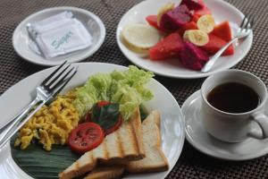 a table with plates of food and a cup of coffee at Dewi Putri House in Ubud
