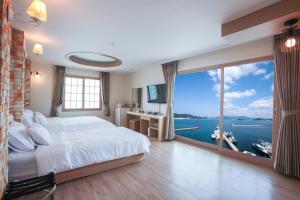sypialnia z dużym łóżkiem i dużym oknem w obiekcie Tongyeong Bay Condo Hotel w mieście Tongyeong