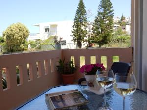 una mesa con 2 copas de vino en el balcón en Charisma Apartment, en Plataniás