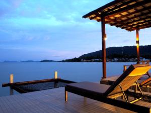 a deck with a bench and a chair on the water at Fresh House in Ko Lanta