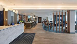 un restaurante con un bar con mesas y sillas en Hyatt Place London Heathrow Airport en Hillingdon