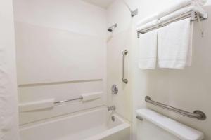 a white bathroom with a toilet and a towel rack at Super 8 by Wyndham Coshocton Roscoe Village in Coshocton