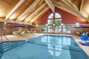 une grande piscine intérieure avec des tables et des chaises dans l'établissement AmericInn by Wyndham Greenville, à Greenville