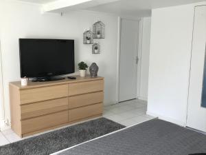 a flat screen tv sitting on top of a wooden dresser at Apartment 36 m² in Bretenière