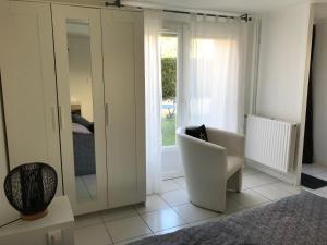 a living room with a white chair and a mirror at Apartment 36 m² in Bretenière