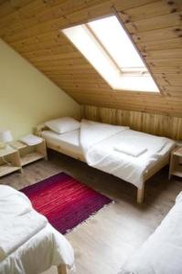 a attic bedroom with two beds and a window at Guest House Magones in Preiļi