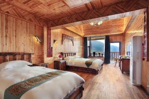 een slaapkamer met 2 bedden in een kamer met houten wanden bij Baike Boutique Hotel in Longsheng