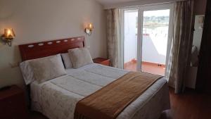 a bedroom with a large bed with a large window at Hotel Avenida in Sabaris