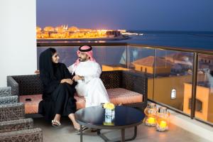 a man and woman sit on a balcony overlooking the ocean at The Grove Resort Bahrain in Manama
