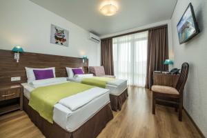 アナパにあるSea Breeze Resortのベッド2台とデスクが備わるホテルルームです。