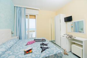 a bedroom with a bed and a desk and a window at Hotel Embassy in Cesenatico