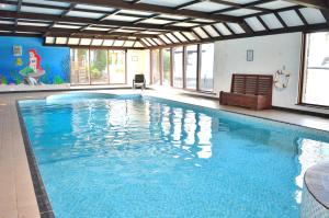 a large pool with blue water in a room with windows at Three Gates Farm Holiday Cottages in Huntsham