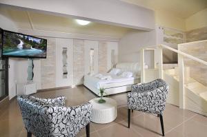 a room with a bed and two chairs and a television at Ahuzat Katamar Ifrach in Ya‘ara