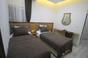 um quarto de hotel com duas camas e um espelho em Gulistan Hotel em Zara