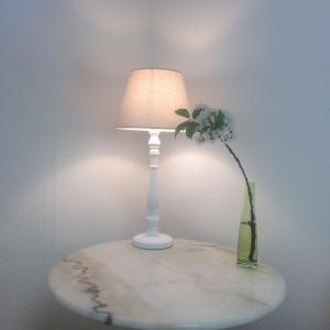 uma mesa com um candeeiro e um vaso com uma flor em D&E Rooms em Schwechat