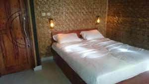 a bed with white sheets and pillows in a room at Aryasuta Bungalow in Tetebatu