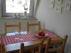 una mesa de madera con un plato de tomates y copas de vino en Ferienwohnung Spatzennest en Wesel