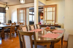 una sala da pranzo con tavoli, sedie e finestre di Mojo Lodge Hakuba a Hakuba