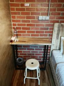 a small table with a stool next to a brick wall at The Rise Room in Kuala Terengganu