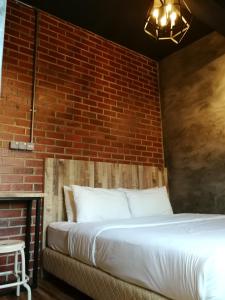 クアラ・トレンガヌにあるザ ライズ ルームのレンガの壁のドミトリールームのベッド1台分です。