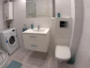 y baño blanco con lavabo y lavadora. en Apartament Jasny, en Częstochowa