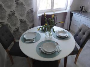 une table blanche avec des assiettes et un vase de fleurs dans l'établissement Apartament Jasny, à Częstochowa