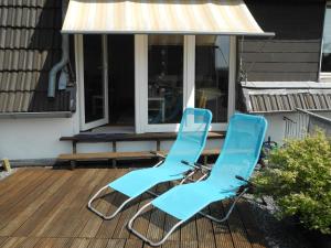 dos sillas azules sentadas en la cubierta de una casa en Ferienwohnung Spatzennest, en Wesel