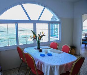 Beautiful Galilea في Deir Ḥannā: طاولة مع إناء من الزهور في غرفة مع نوافذ