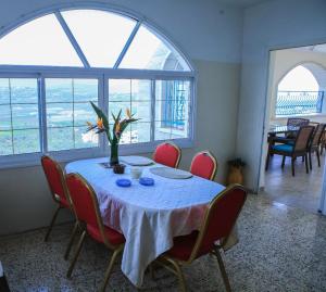 a dining room table with red chairs and a table with flowers on it at Beautiful Galilea in Deir Ḥannā
