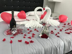 ein Bett mit roten Rosen, Champagner und Schwänen darauf in der Unterkunft La Suite Tropea in Tropea